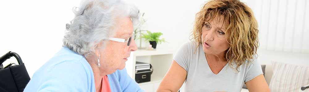 Forty-something female caregiver talking with her elderly mother about caregiving