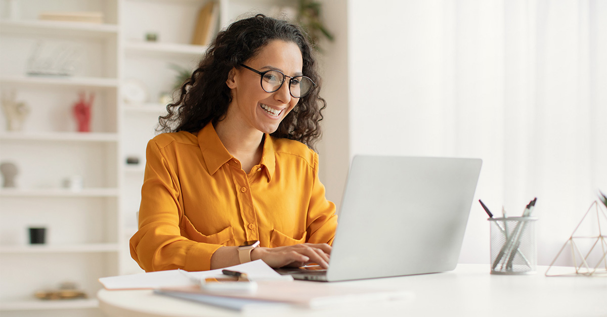 Woman smiling while on laptop in home setting